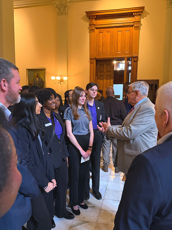 A group of President's Torch Society students engage in a conversation with an official inside the Georgia State Capitol.